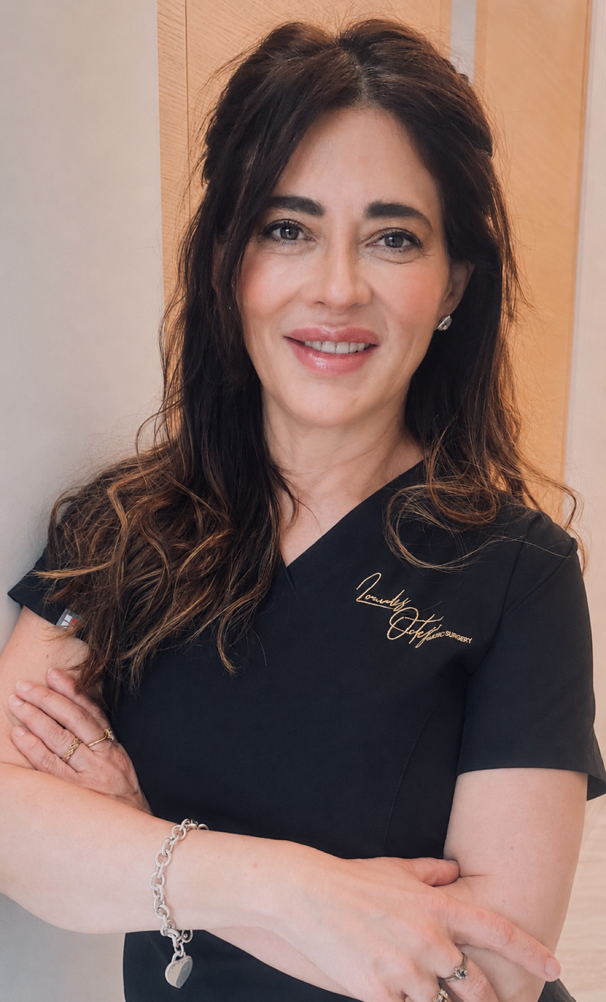 Dra. Lourdes Ortega, cirujana plástica certificada, con su firma bordada en el uniforme